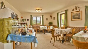 A dining area with multiple tables, chairs, and a green cabinet with glassware. - Haus Rottensteiner (Renon)
