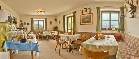 A dining area with multiple tables, chairs, and a green cabinet with glassware.