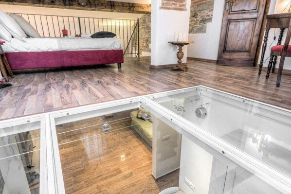 Une chambre à coucher avec un lit, un plancher en bois, une vitrine et un mur en pierre.
