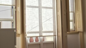 A room with a large window, a door, and a view of the outside. - Apartamento Casino Praia I, center, wi-fi, cable TV (Figueira da Foz)