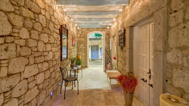 A stone-walled corridor with a bench, a table with chairs, and a door leading to another room. - Beyaz Han Hotel (Cesme)