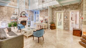 A spacious living area with a fireplace, stone walls, and a balcony. - Beyaz Han Hotel (Cesme)