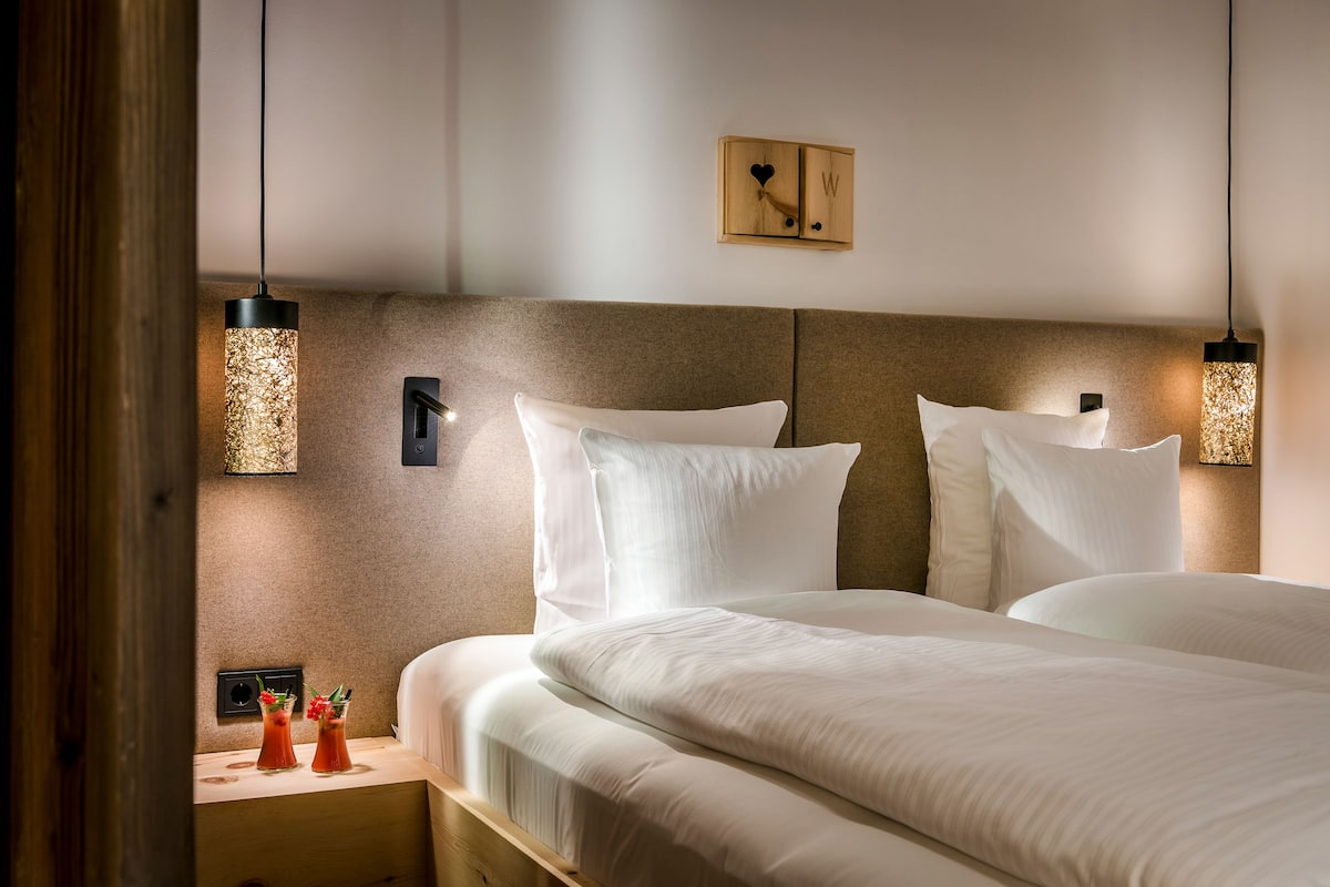 Una habitación de hotel con una cama grande, dos mesitas de noche y un reloj en la pared.