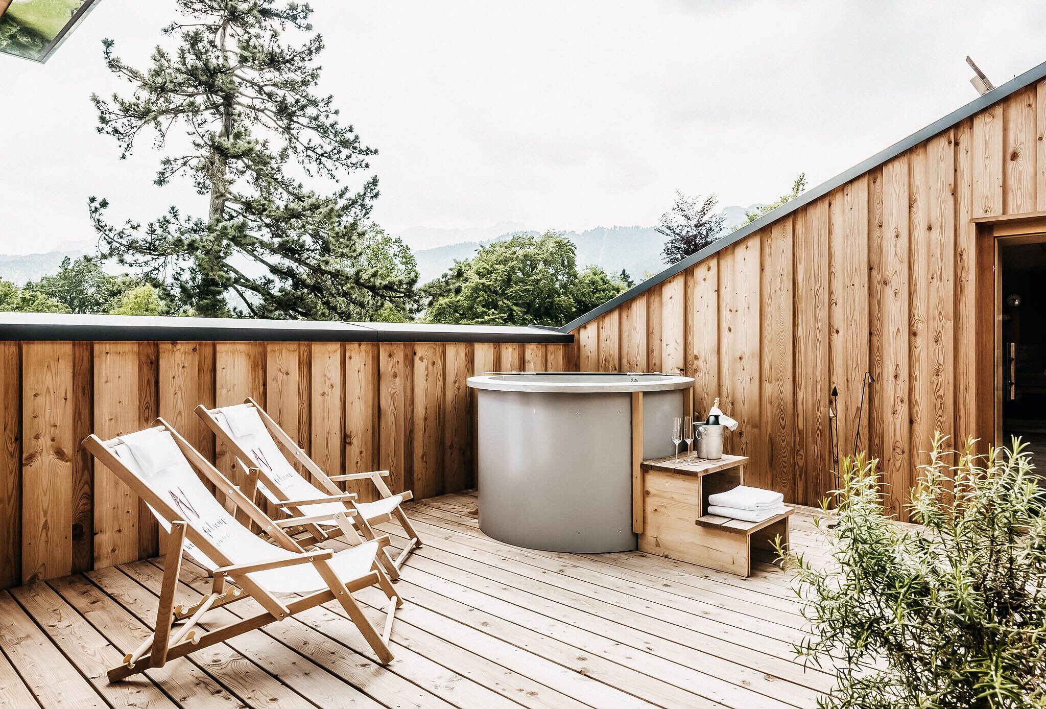 A wooden deck with lounge chairs and a hot tub.