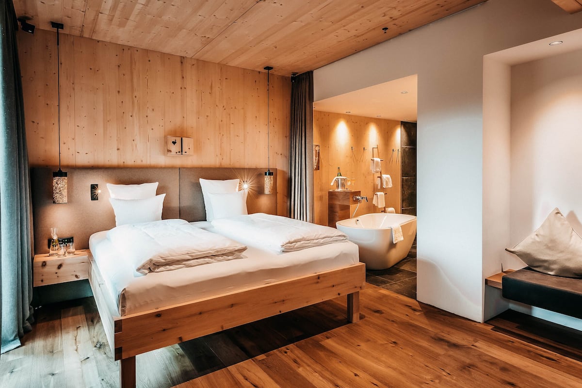 Un dormitorio moderno con una cama de madera, una bañera integrada y un diseño minimalista.