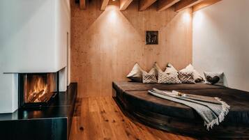 Une pièce chaleureuse avec une cheminée, un canapé avec des coussins et des murs en bois.