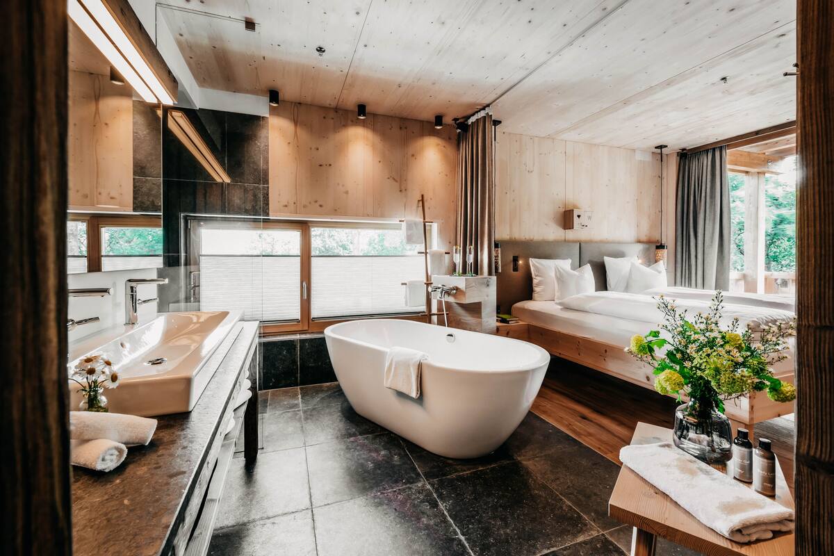 Un baño moderno con una bañera independiente, un tocador con espejo y un amplio ventanal que proporciona luz natural.