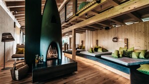 A modern interior with a fireplace, wooden floors, and a balcony with railings. - Werdenfelserei (Garmisch-Partenkirchen)
