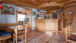 A wooden interior with a bar area, wooden furniture, and tiled flooring. - Cesa Rotic (Canazei)