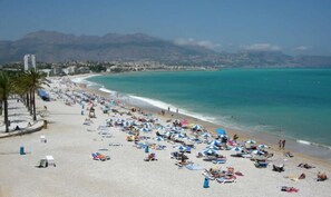 A beach with numerous umbrellas and sun loungers, a clear blue sea, and mountains in the background. - 🌞 Spacious 3-room apartment in a luxury building, 150m beach, internet🌞 (Albir)