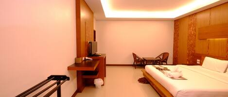 A hotel room with a bed, a desk, a chair, and a TV.