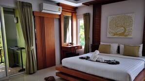 A modern hotel room with a large bed, a wooden desk, a mirror, and an air conditioning unit. - The Peace Tara House (Ko Lanta)