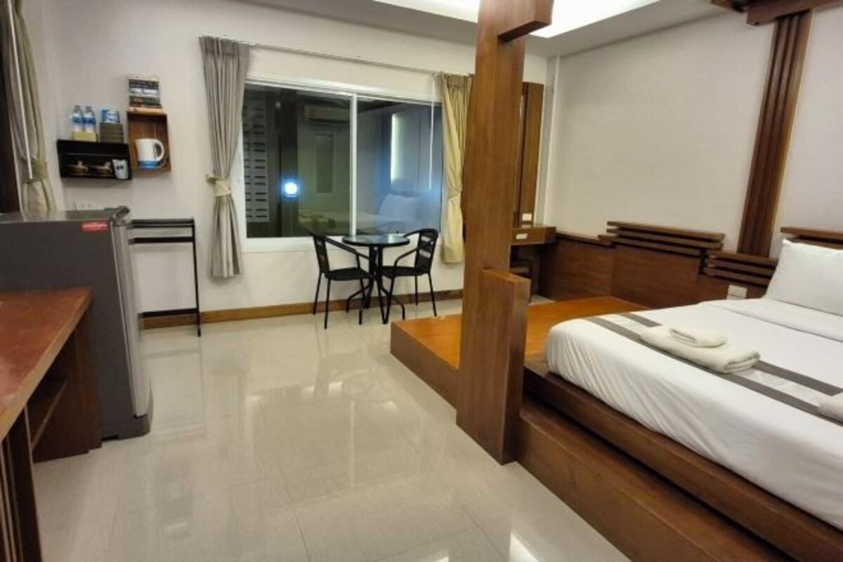 A hotel room with a bed, a desk, a chair, and a window with curtains.