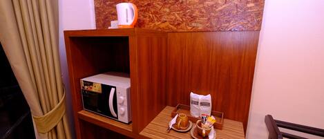 Eine Eckküche mit einer Mikrowelle, einer Kaffeemaschine und einem kleinen Tisch mit Frühstücksangeboten.