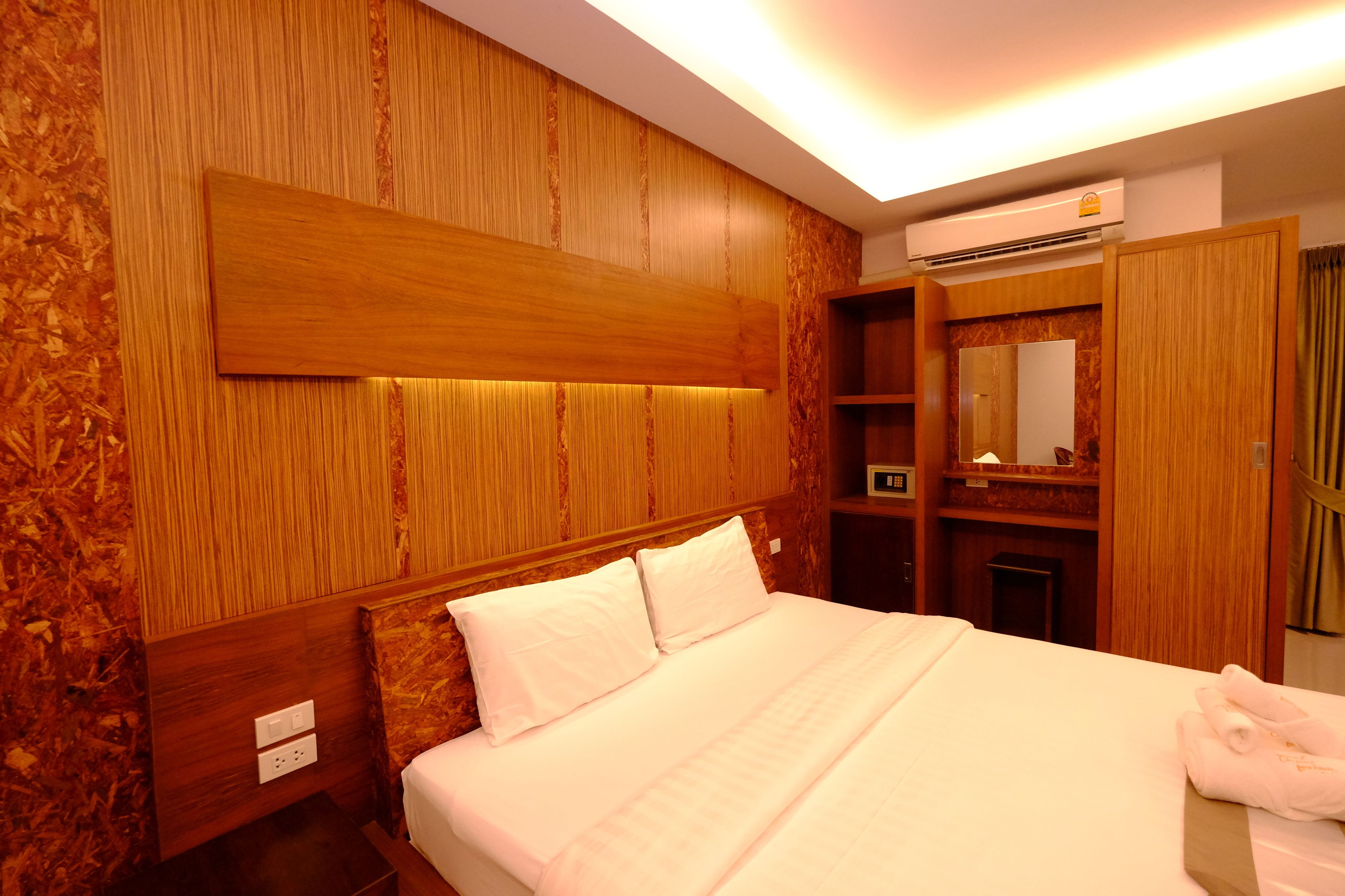 Une chambre d’hôtel avec un grand lit, des boiseries, une armoire intégrée et un appareil de climatisation.