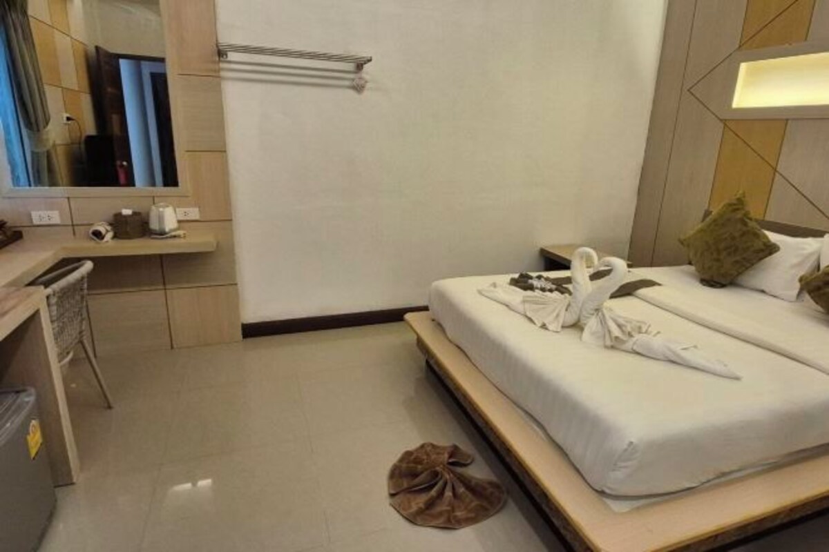 Une chambre d’hôtel comprenant un lit, une table de chevet, un miroir et un porte-serviettes.