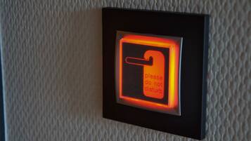 A wall-mounted light switch with a red glow and a sign that says "please do not disturb."