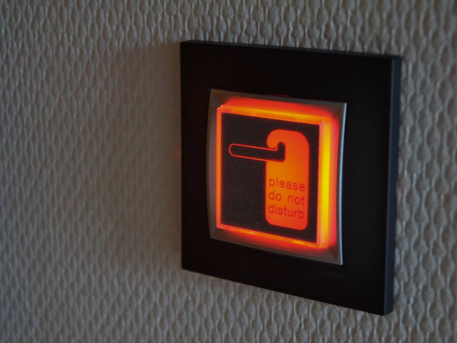 A wall-mounted light switch with a red glow and a sign that says "please do not disturb."
