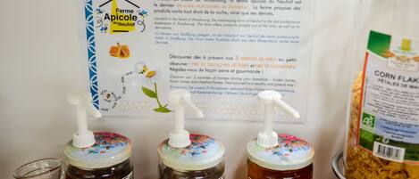 Three honey jars labeled 'Miel de Châtaignier', 'Miel de Forêt', and 'Miel de Tilleul' with a honey dispenser in front of them.