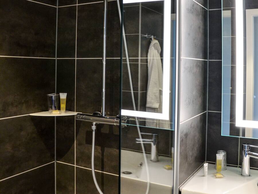 A modern bathroom with a glass-enclosed shower, a large mirror, and a white sink.