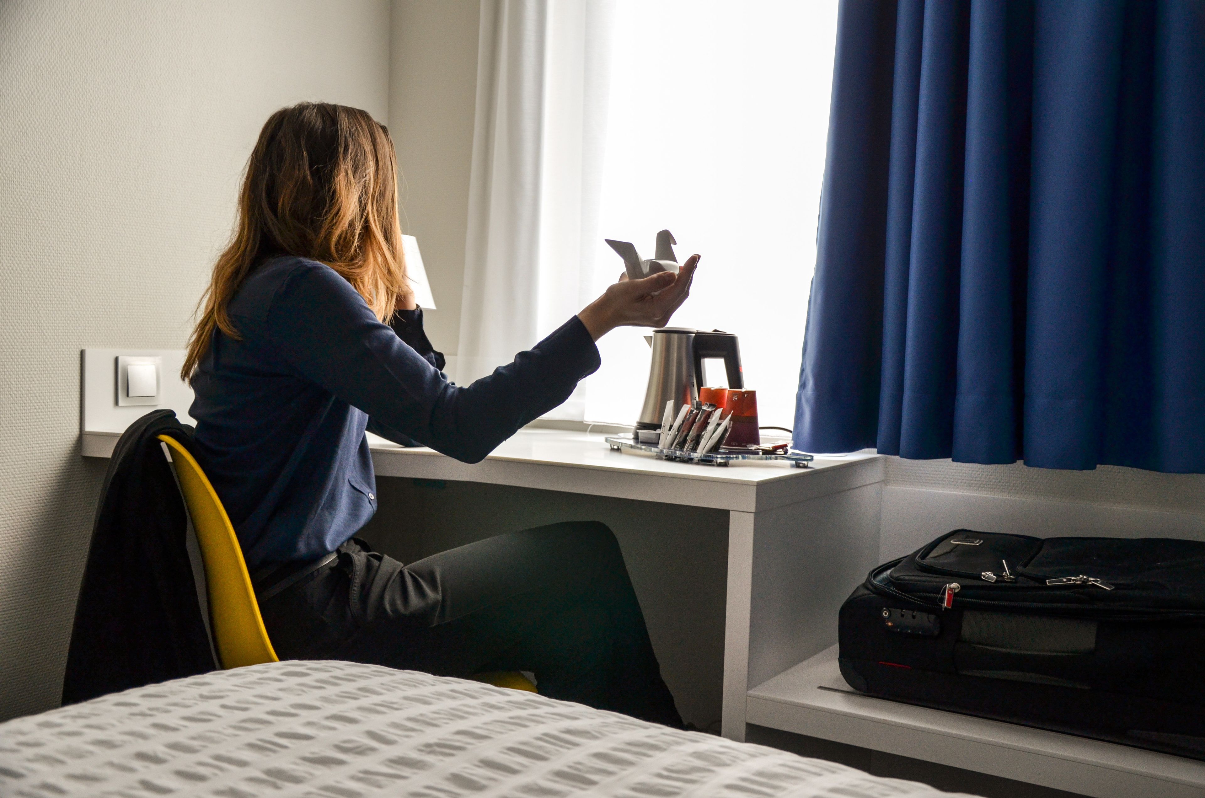 En person sidder ved et skrivebord med en bærbar computer, en elkedel og en kaffemaskine.