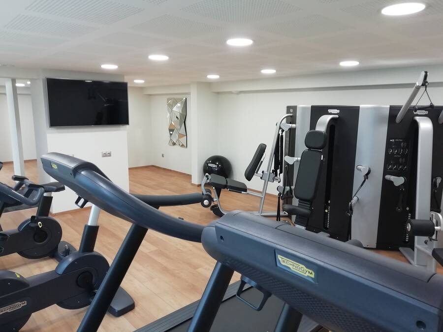 A gym with exercise equipment, a flat-screen TV, and a mirror.