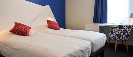Habitación de hotel con dos camas, un escritorio y una silla.