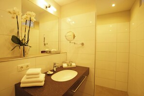 Ein modernes Badezimmer mit Waschbecken, Spiegel und einer Orchideen-Vase.