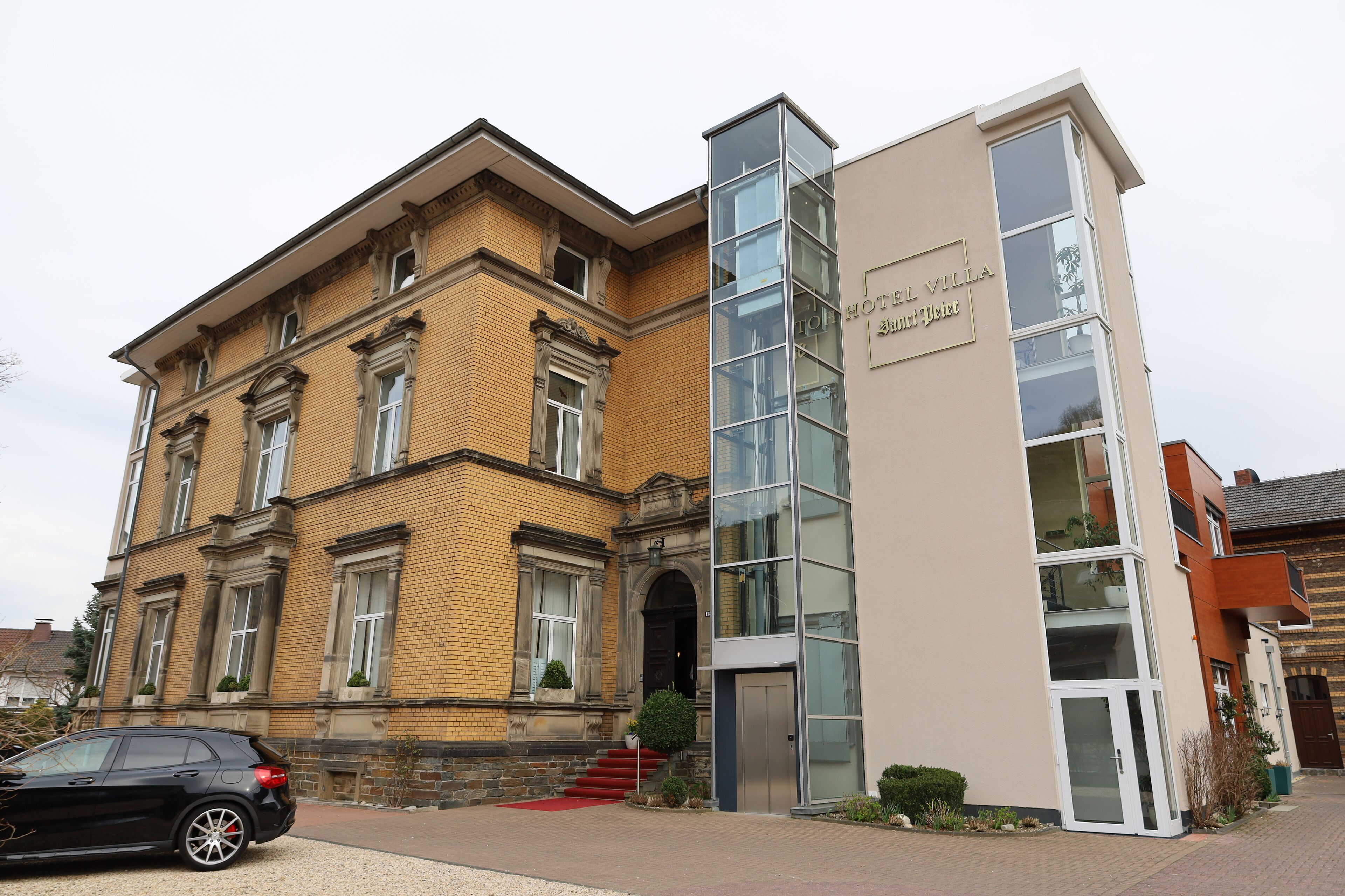 A hotel with a classic brick facade and a modern glass extension.