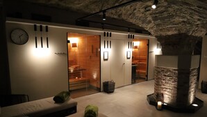 A spa room with a stone pillar, a clock, and a massage table. - Hotel Villa Sanct Peter (Bad Neuenahr-Ahrweiler)