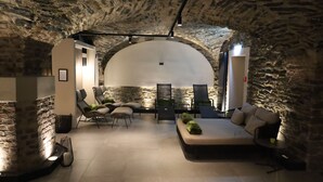A cozy, stone-walled room with a curved ceiling, a sofa, chairs, and a small table. - Hotel Villa Sanct Peter (Bad Neuenahr-Ahrweiler)