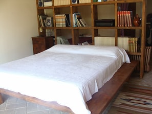 Ein Schlafzimmer mit einem großen Bett, Holzregalen und einer Heizung.