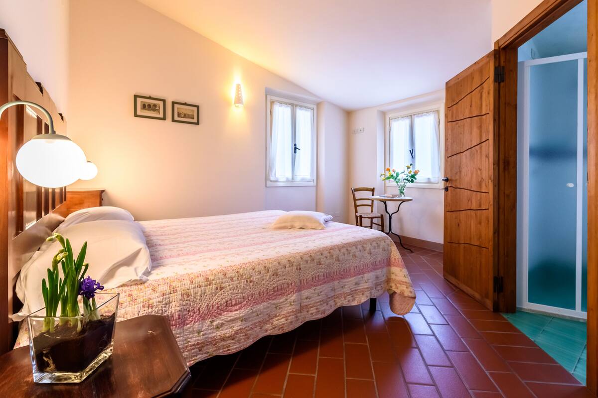 A bedroom with a bed, bedside table, lamp, and a window with curtains.