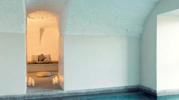 Un área de spa con un banco de piedra, velas y una pequeña zona de estar.
