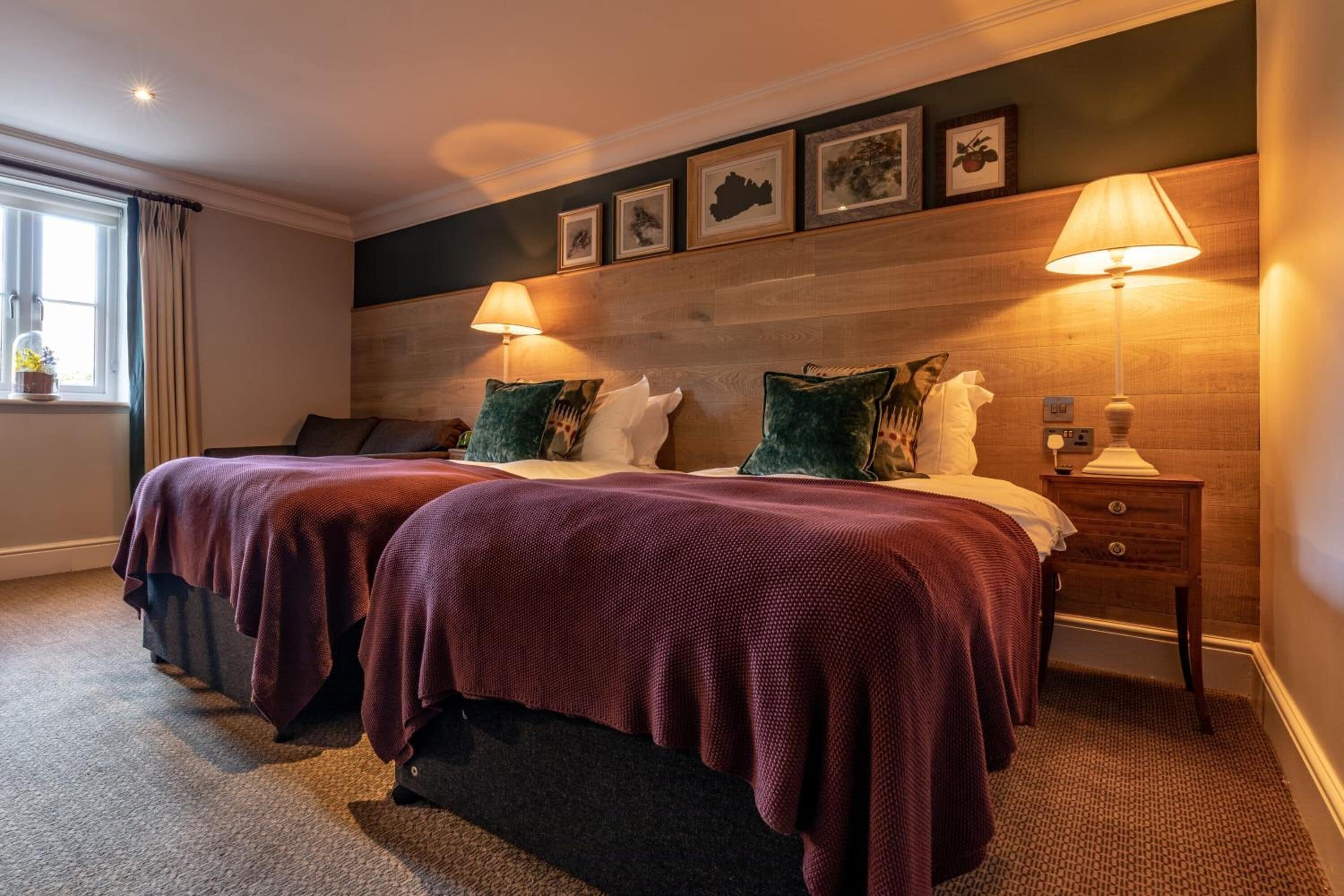 A double bed with two pillows, a nightstand with a lamp, and a window with curtains.