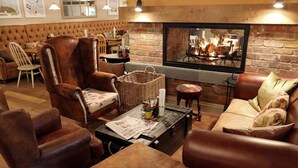 Ein gemütlicher Lounge-Bereich mit Ledersofas, einem Kamin und einer Ziegelwand.