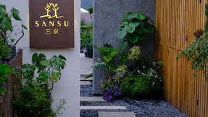 A sign with the name 'SANSU' and Chinese characters, surrounded by lush greenery and a stone pillar. - Hangzhou Sansu Hotel (Hangzhou)