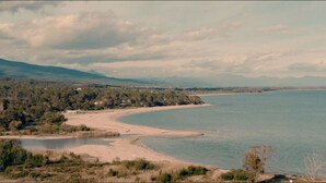Un paisaje costero con playa, un lago pequeño y un área boscosa.