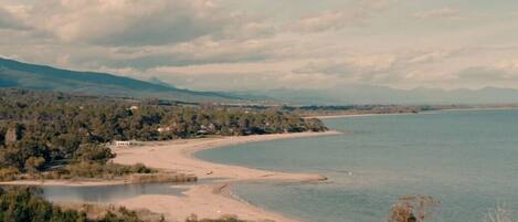 A coastal landscape with a beach, a small lake, and a forested area.