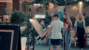 Un restaurante con terraza, un cartel de menú y un piano.