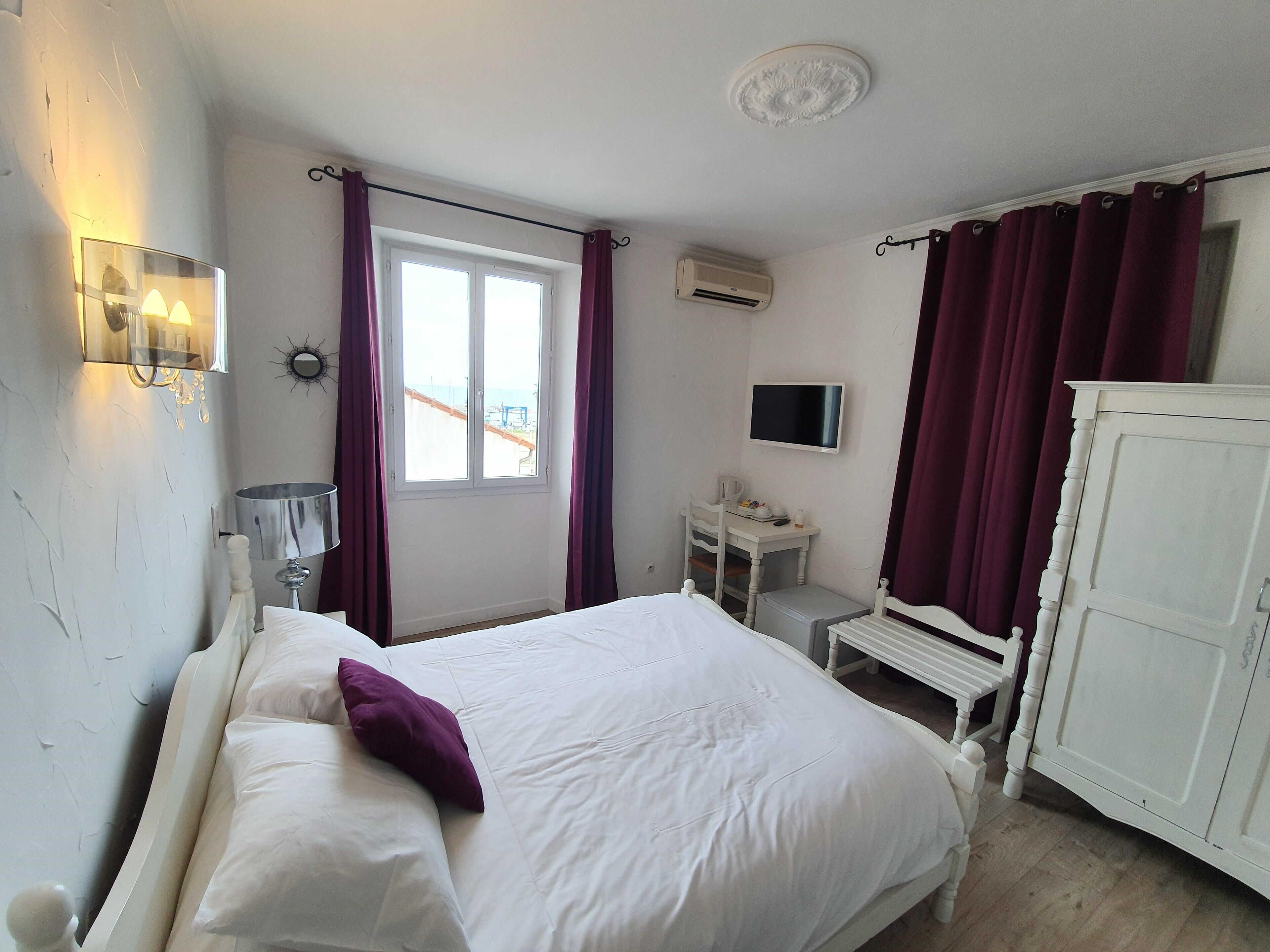 Une chambre à coucher comprenant un lit, un bureau, une chaise, une télévision et une armoire.