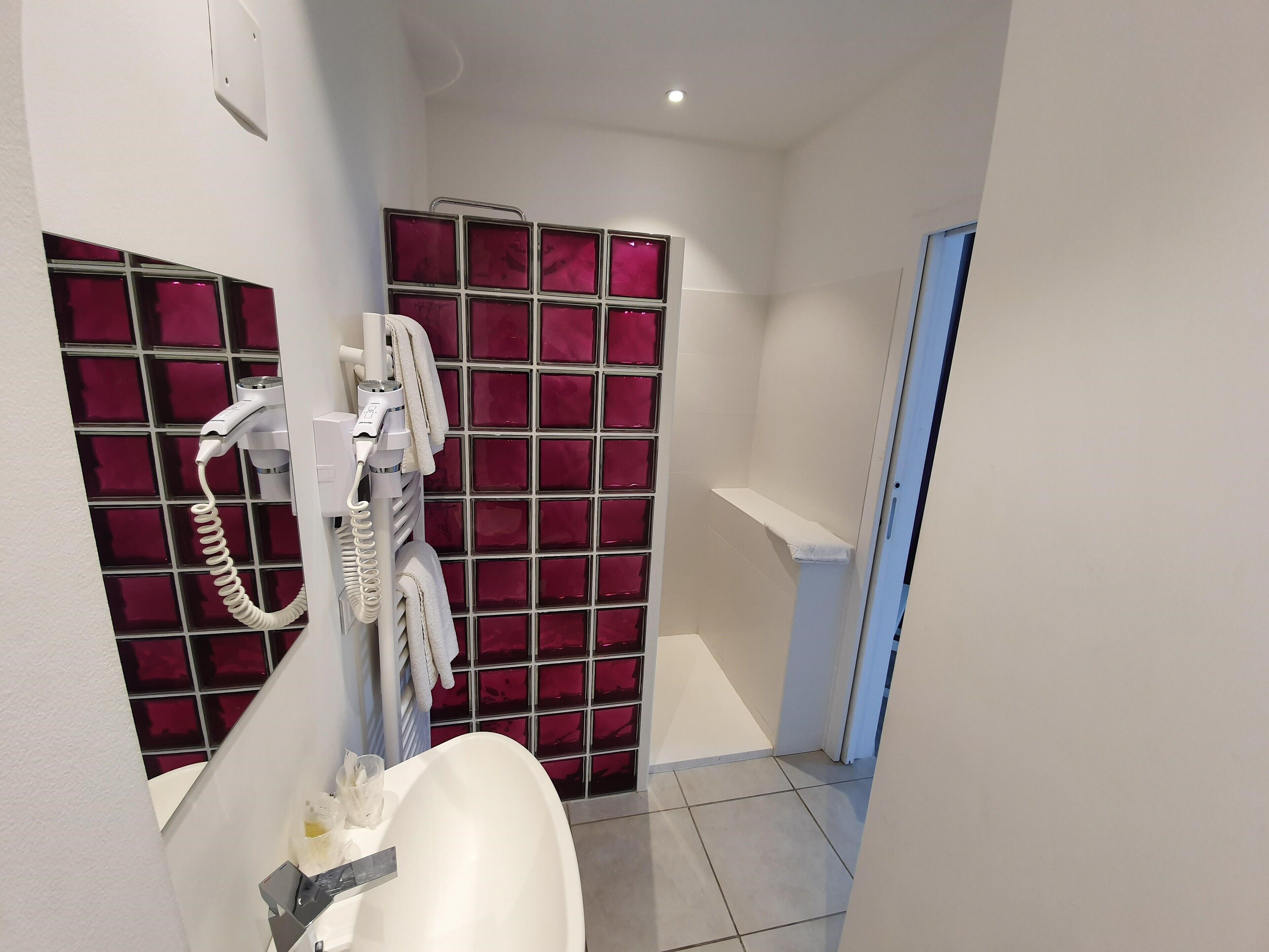 A bathroom with a white sink, a hairdryer, and a mirror.
