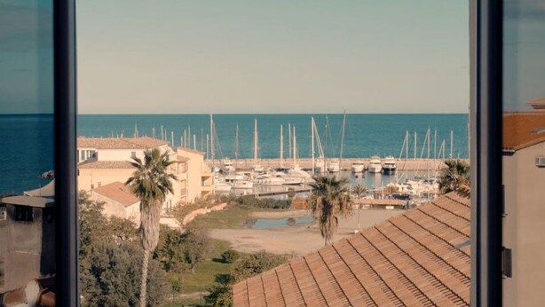 Un puerto deportivo con barcos, una playa y edificios con tejados de tejas.