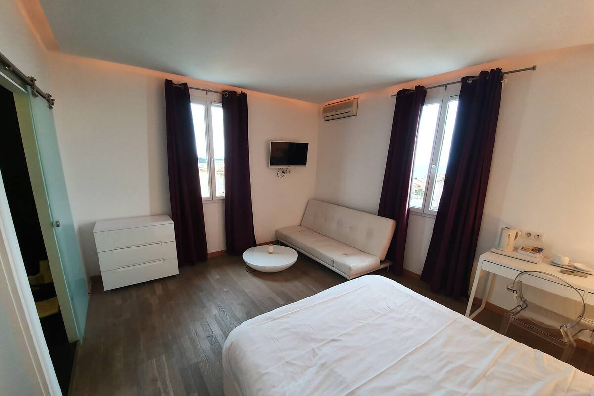 Habitación de hotel con cama, sofá, una mesita, televisor y aire acondicionado.