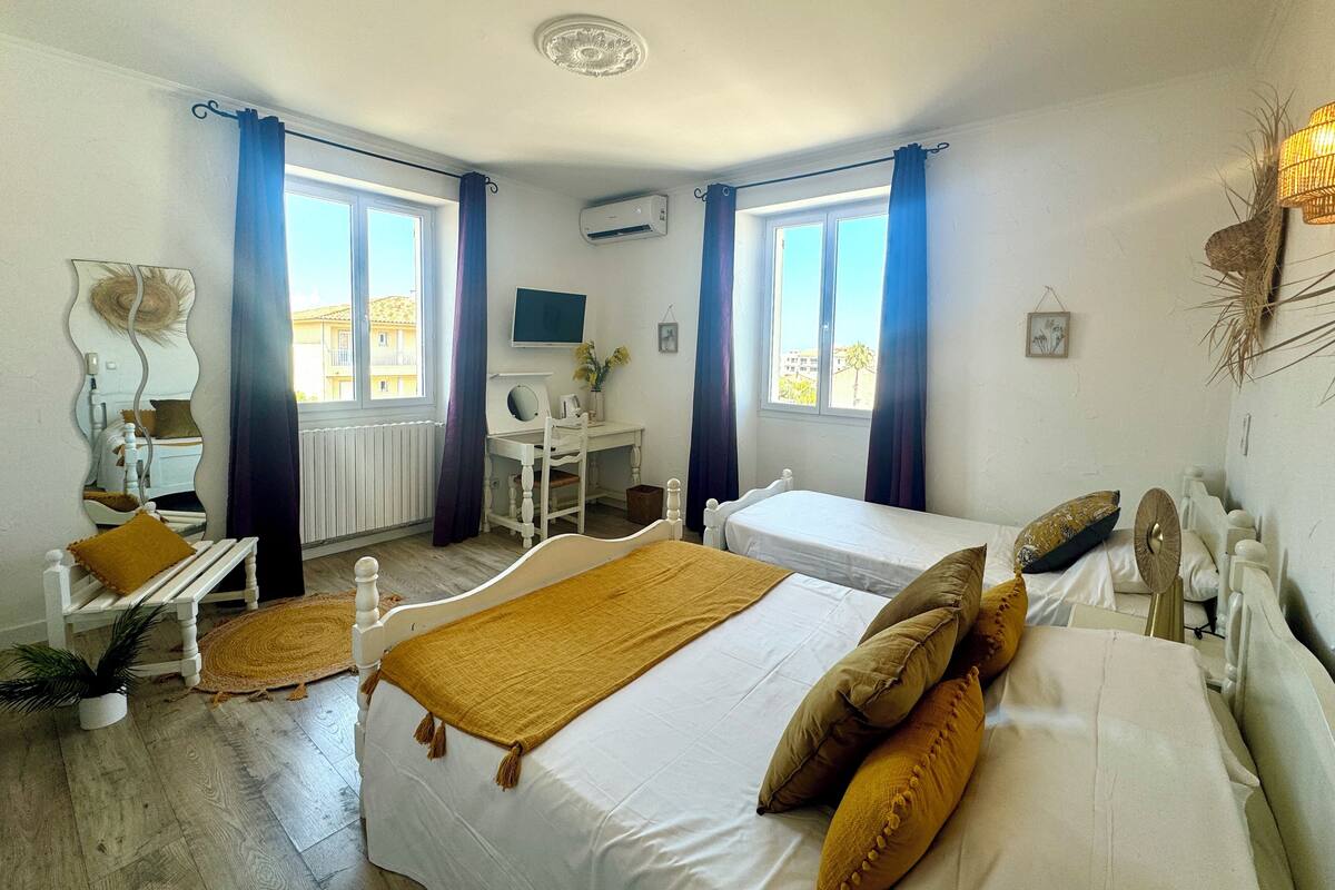 Un dormitorio con dos camas, un escritorio, una silla, un espejo y una ventana con cortinas.