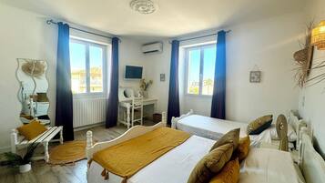 A bedroom with two beds, a desk, a chair, a mirror, and a window with curtains.