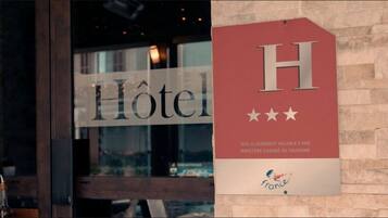 Een hotelschild met de tekst 'Hôtel' en een rood bord met de letter 'H' en drie sterren, wat een 5-sterrenclassificatie aangeeft.