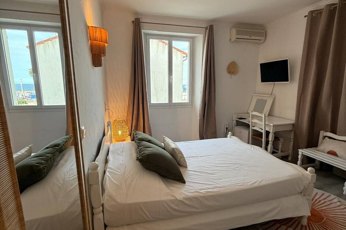 Un dormitorio con cama, escritorio, silla, televisor y ventana.