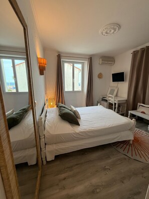 Un dormitorio con cama, escritorio, silla, televisor y ventana.