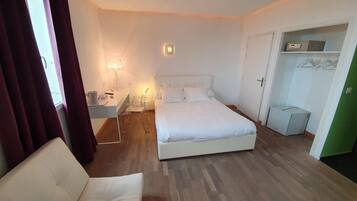 A bedroom with a bed, bedside table, lamp, and a wardrobe.